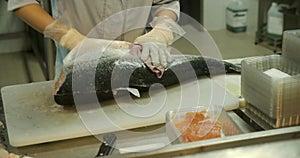Close-up shot of a woman worker's hand in a market factory, a woman stands on the process of cutting a salmon and