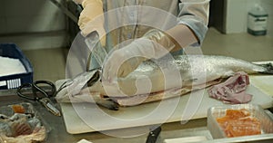 Close-up shot of a woman worker's hand in a market factory, a woman stands on the process of cutting a salmon and