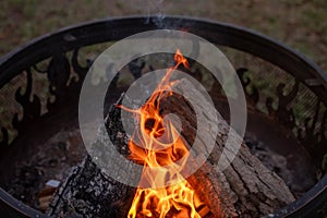 A Close up shot of wood burning in an outdoor fire pit with flames