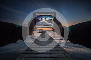 Close-up shot of working tablet on sunset and sea background