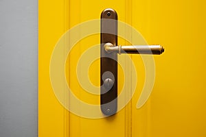 Close-up shot of yellow color door with vintage door knob.