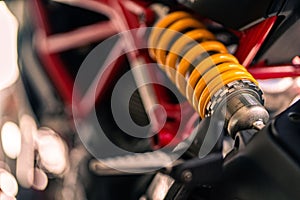 Close-up shot of a yellow suspension shock absorber attached on a motorcycle