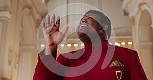 Close up shot of young afro American man singing and moving hands emotionally. Male spiritual gospel singer wearing in