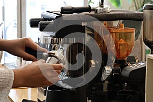 Close-up shot of young beautiful baretta making coffee with modern coffee machine.