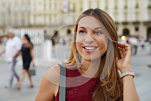 Close up shot of young beautiful surprised woman looks away against city blurred background