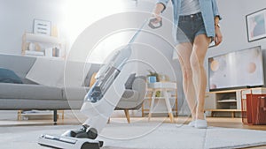 Close Up Shot of a Young Beautiful Woman in Jeans Shirt and Shorts Vacuum Cleaning a Carpet in a B