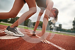 Close up shot of young female athlete preparing for the race on track field in the daytime