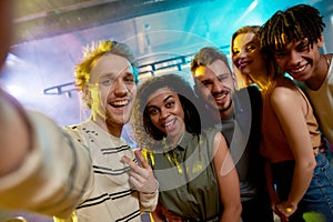 Close up shot of young men and women smiling while taking selfie. Multiracial group of friends hanging out at party in