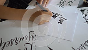 Close up shot of a young woman calligraphy writing on a paper using lettering technique. She writes Love yourself