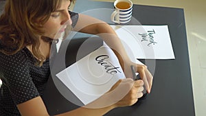 Close up shot of a young woman calligraphy writing on a paper using lettering technique. She writtes Create more