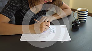 Close up shot of a young woman calligraphy writing on a paper using lettering technique. She writtes Create more