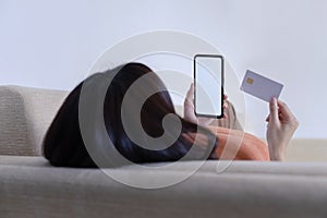 Close-up shot of young woman making online payment by mobile smart phone and credit card. White screen mockup smartphone for