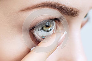 Close-up shot of young woman wearing contact lens.