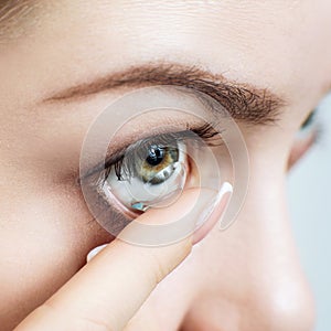 Close-up shot of young woman wearing contact lens.