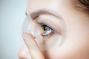 Close-up shot of young woman wearing contact lens.