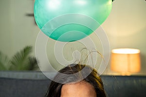 close up shoto of kids playing by placing balloon to attracting hair - conept of static cling home science experiment