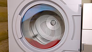 Close-up shots of a spinning dryer drum with blue and red clothes inside.