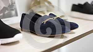 A close up showcase with camera floating of a luxury blue shoes standing on a shelf inside a clothing boutique