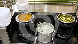 Close-up. showcase with freshly prepared first courses, soups in tureens, in self-service cafeteria or buffet restaurant