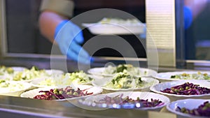 Close-up, showcase with salads in canteen, mess hall, cafeteria, Food Buffet resturant. buffet worker lays out food on