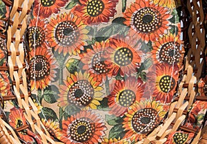 Horizontal close up of a sunflower cloth and wicker basket.