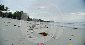 Close-up shows trash and plastic trash bags strewn across the beach. Shoote of water area environmental pollution