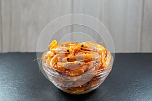Close-up of shrimp in a glass bowl on a dark stone background. Seafood, healthy food concept. Horizontal photo, macro.