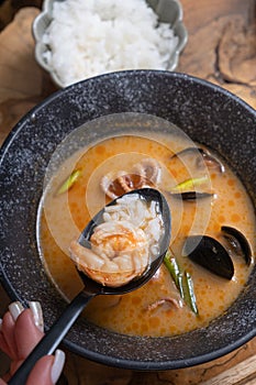 Close up shrimp and rice on spoon on the background of tom yum soup