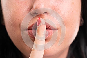 Close-up of shush gesture with finger over mouth made by woman