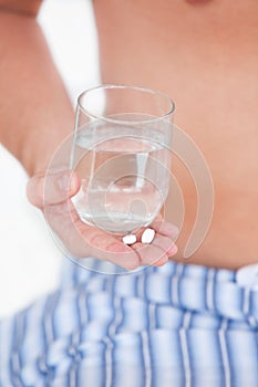 Close-up of a sick man holding pills and water