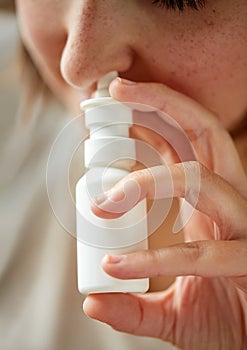 Close up of sick woman using nasal spray