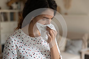Close up sick young woman blowing nose, holding paper napkin