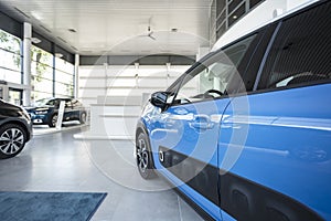 Close-up of a side door of a blue car on a spacious display in a