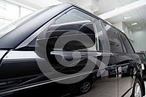 Close-up of the side left mirror with rear veiw 3d camera and window of the car body black SUV on the parking after washing in