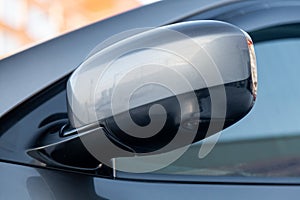 Close-up of the side left mirror with rear veiw 3d camera and window of the car body gray SUV on the parking after washing in auto