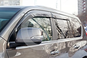 Close-up of the side left mirror with rear veiw 3d camera and window of the car body gray SUV on the parking after washing in auto