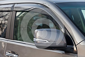 Close-up of the side left mirror with rear veiw 3d camera and window of the car body gray SUV on the parking after washing in auto