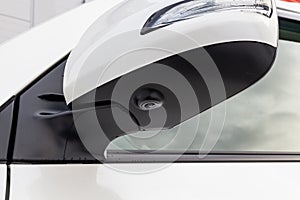 Close-up of the side left mirror with rear veiw 3d camera and window of the car body white SUV on the parking after washing in