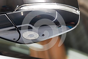 Close-up of the side left mirror with turn signal repeater, rear veiw 3d camera and window of the car body gray SUV on the parking