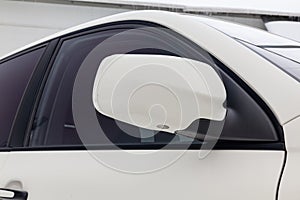 Close-up of the side left mirror with turn signal repeater and window of the car body white SUV on the street parking after