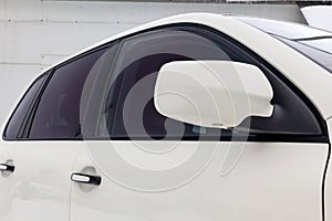 Close-up of the side left mirror with turn signal repeater and window of the car body white SUV on the street parking after