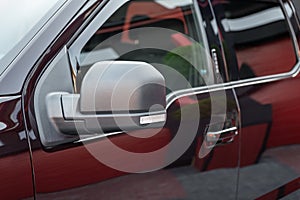 Close-up of the side left mirror and window of the car body black SUV on the street parking after washing. Road safety