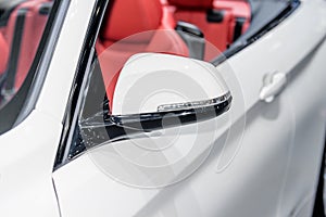 Close up of side mirror of white car with turn signal.