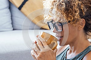 Close up side portrait of attractive blonde adult woman drinking coffee or tea at home alone smiling and enjoying the moment.