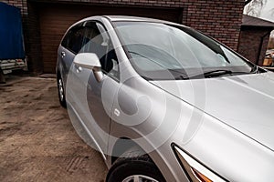 Close-up of the side right mirror and window of the car body silver sedan on the street parking after washing and detailing in