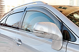 Close-up of the side right mirror and window of the car body silver SUV on the street parking after washing and detailing in auto