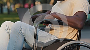 Close-up side view of adult paralyzed African American man typing text on computer keyboard communicates on social