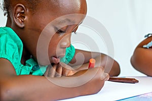 Close up side view of african girl painting with crayon