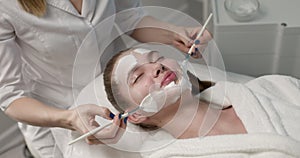 close up side view on attractive young woman lying with closed eyes in spa salon