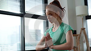 Close-up side view of calm young woman meditating in lotus position sitting on floor with closed eyes at home practicing